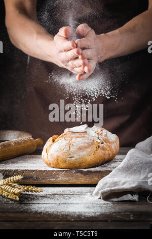 Baker cooking bread. Man slaps flour over the dough. Man's hands Making bread Stock Photo