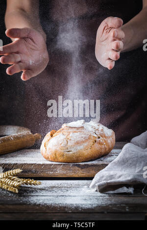 Baker cooking bread. Man slaps flour over the dough. Man's hands Making bread Stock Photo