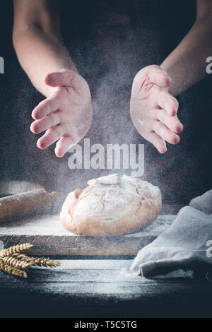 Baker cooking bread. Man slaps flour over the dough. Man's hands Making bread Stock Photo