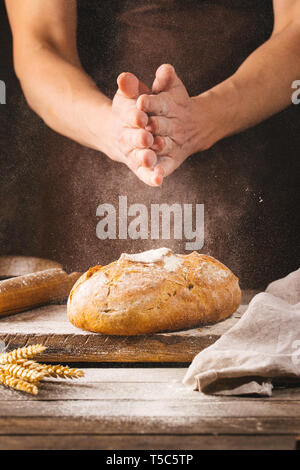 Baker cooking bread. Man slaps flour over the dough. Man's hands Making bread Stock Photo