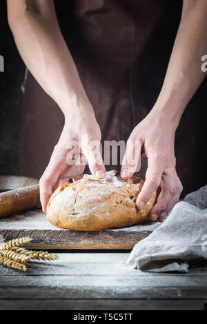 Baker cooking bread. Man slaps flour over the dough. Man's hands Making bread Stock Photo