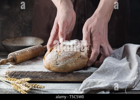 Baker cooking bread. Man slaps flour over the dough. Man's hands Making bread Stock Photo