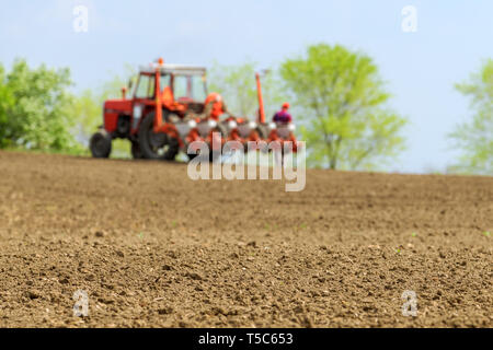 Farmer repairing tractor with seeder in field during corn crop planting, selective focus Stock Photo