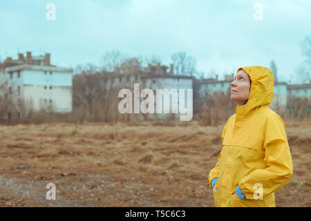 Woman in yellow raincoat looking up at rainy clouds while the raindrops are falling on her face Stock Photo