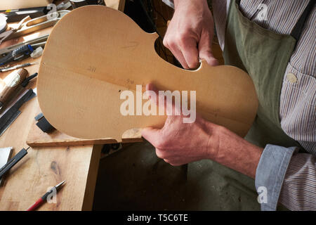 Violin maker at work in London, UK, carving the back of a violin Stock Photo