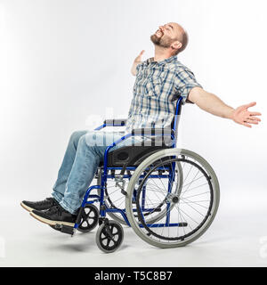 Man sitting in a wheelchair with arms raised and eyes closed. smiling and positive expression. Stock Photo