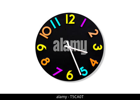 A black wall clock isolated on a white background. Hours in different colors. Stock Photo