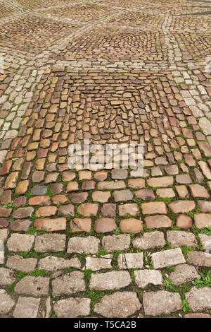 Old square paved with large cobblestones and grass between them Stock Photo