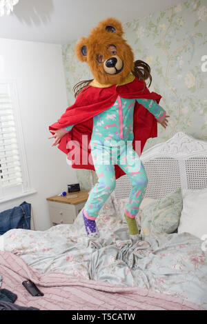 super hero bear jumping on bed Stock Photo