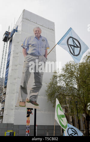 An image of veteran wildlife and environmental broadcaster Sir David Attenborough is held high in Parliament Square during the week-long protest by climate change activists with Extinction Rebellion's campaign to block road junctions and bridges around the capital, on 23rd April 2019, in London England. Stock Photo