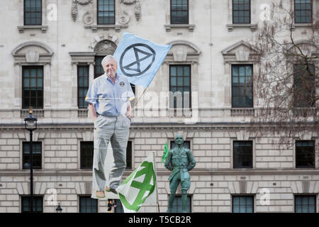 An image of veteran wildlife and environmental broadcaster Sir David Attenborough is held high in Parliament Square next to the statue of Field Marshal Jan Christiaan Smuts, the South African and British Commonwealth statesman, military leader and philosopher, during the week-long protest by climate change activists with Extinction Rebellion's campaign to block road junctions and bridges around the capital, on 23rd April 2019, in London England. Stock Photo