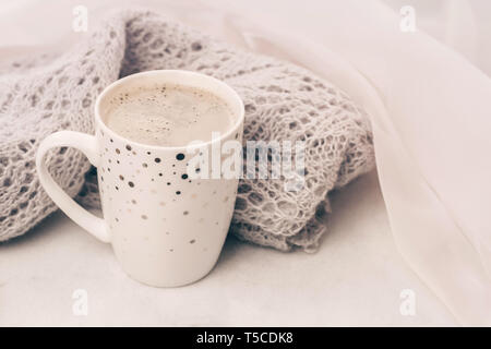 Cozy pastel knitwear and a cup of coffee on white marble windowsill. Close-up. Stock Photo