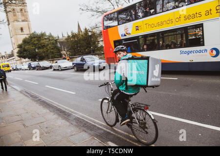 Oxford, United Kingdom - Mar 3, 3017: Rear view of Young male cyclist delivering food fast to client via Deliveroo App - commuting fast in the university city with big thermo bag with Deliveroo logo Stock Photo