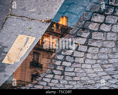Abstract Cinematic Reflection of luxury parisian apartments building in Haussmannian style in the water poodle on the cobblestone road pavement  Stock Photo