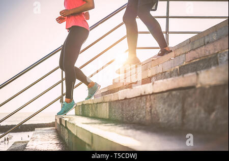 View of runners legs having a workout session on city stairs outdoor - Close up of people running at sunset Stock Photo