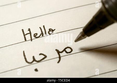 Beginner Arabic language learner writing Hello word in abjad Arabic alphabet on a notebook close-up shot Stock Photo