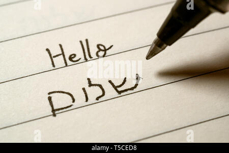 Beginner Hebrew language learner writing Hello shalom word in Hebrew alphabet on a notebook close-up shot Stock Photo