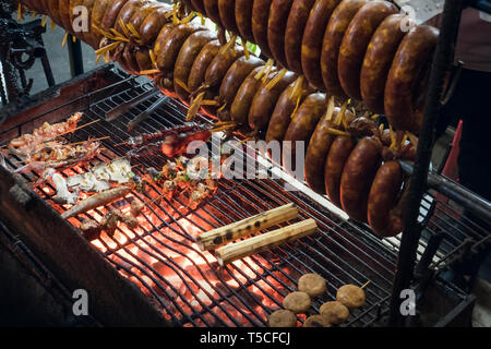 Smoked sausage hanging over the grill. The process of Smoking sausage. Cooking street food on grill Stock Photo