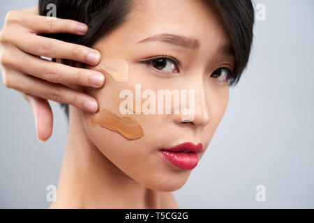 Woman applying foundation swatches on cheek Stock Photo