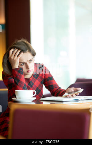 Frustrated young woman sitting in coffeeshop Stock Photo