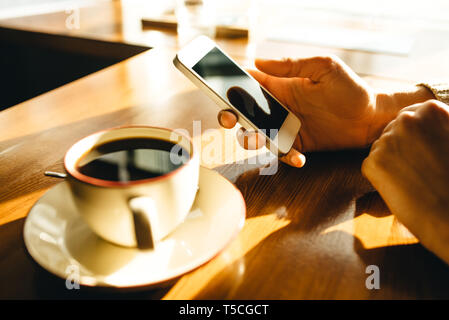 Woman using smartphone on wooden table in cafe. Close-up image with social networks concept Stock Photo