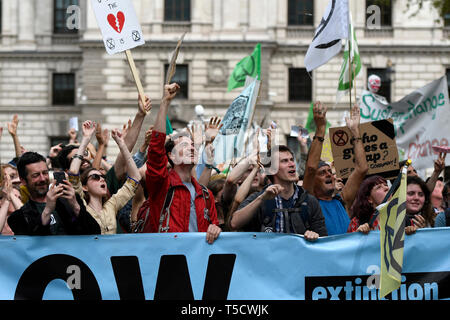 Climate Change protesters are seen behind a large banner shouting slogans during the Extinction Rebellion march in London.  Extinction Rebellion protesters march from Marble Arch to Parliament Square, attempting to deliver letters to their MPs. Extinction Rebellion activists were permitted to be in Parliament Square but not to enter Parliament. After several attempts to deliver the letters, the activists reached an agreement with MPs through the police. Ten activists were allowed to deliver the letters in the company of Baroness Jenny Jones (Green party). Philosopher and Green campaigner Ruper Stock Photo