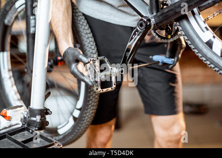 Repairman installing new pedals on a mountain bicycle at the workshop Stock Photo