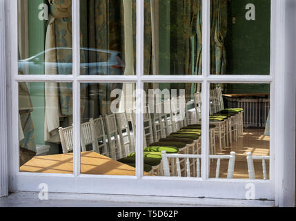 A view through a window  into the assembly rooms in Royal Lemington Spa showing empty chairs with an atmosphere of sadness Stock Photo