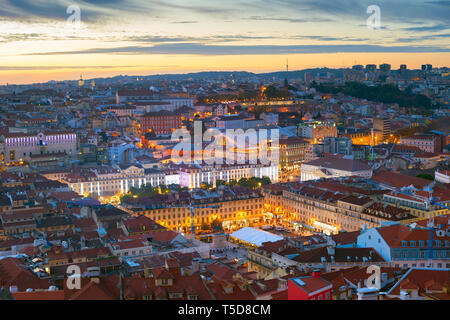 Aerial night cityscape of Lisbon downtown, red rooftops, illuminated Praca do Pedro IV square, afterglow skyline, Portugal