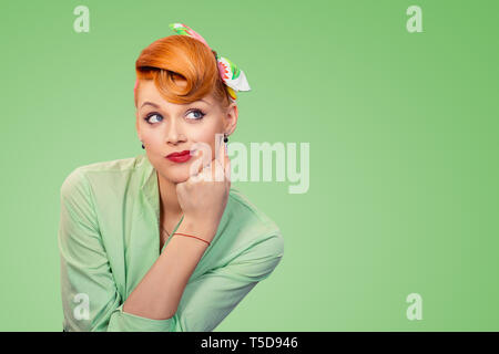 Closeup portrait skeptical confused pin up retro style woman looking suspicious, curiosity on her face mixed with disapproval, isolated on green backg Stock Photo