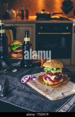 Dinner with Two Patties Cheeseburger and Couple Bottle of Beer on Kitchen Table. Stock Photo
