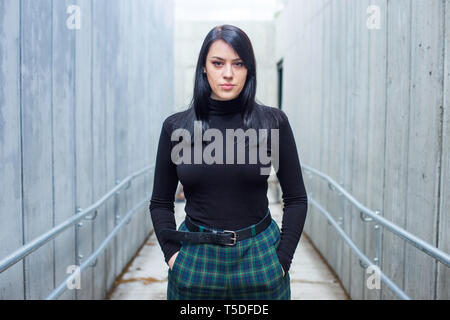 Confident young woman in black shirt and black hair walking on the street to underground in the city. Stock Photo