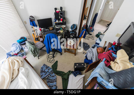 Very messy, cluttered,teenage boy's bedroom with piles of clothes, electronics, music and sports equipment. Stock Photo