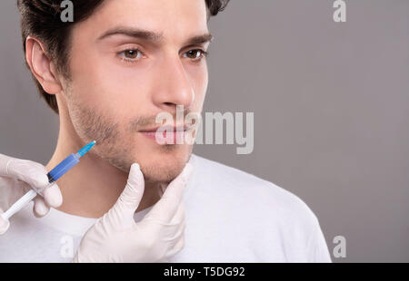 Beautician doing injection to young man face Stock Photo