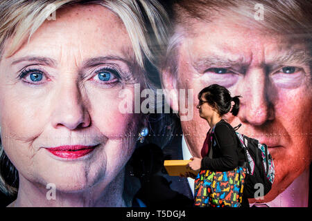 People walks past two portraits of the presidential candidates, pasted on a CNN Airstream trailer outside the debate area. The Democrate and Republican nominees for US President, Hillary Rodham Clinton and Donald John Trump, met on Sep. 26th for the first head to head Presidential Debate at the Hofstra University in Long Island. Stock Photo