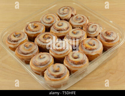 Close up of group of mini cinnamon rolls with icing in plastic container Stock Photo