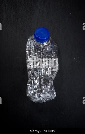 Wrinkled plastic bottle on a black table. Stock Photo