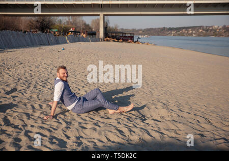 one young man, smiling, laying on beach relaxing. Stock Photo