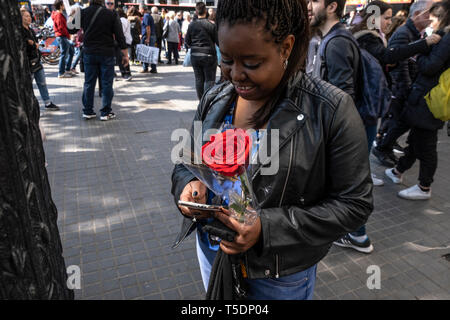 A woman is seen holding a red rose during the Sant Jordi day celebration. The festivity of Sant Jordi is celebrated in conjunction with Book Day and the Fair of Roses, symbols of culture and love.  Knight Saint Jordi died on April 23, 303.The cult of Saint Jordi was established in Catalonia during the 8th century but it is at the end of the 19th century, with the Catalan Renaixença that installed as the most celebrated patriotic, civic and cultural day in Catalonia.  The streets of the cities and towns of Catalunya are filled with stalls with books and roses for sale. Tradition orders that man Stock Photo
