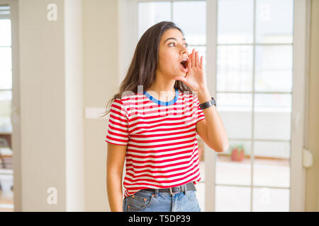Young beautiful woman wearing casual t-shirt shouting and screaming loud to side with hand on mouth. Communication concept. Stock Photo