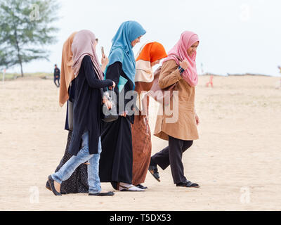 Five Muslim women wearing hijab walking on the beach in the conservative Kelantan State of Malaysia. Stock Photo