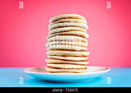 High stack of pancakes on a pink and blue background Stock Photo