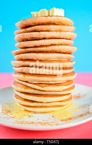 High stack of pancakes on pink and blue background Stock Photo
