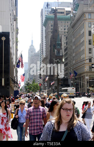 People walking on 5th Ave. in New York City, USA. Fifth Avenue Presbyterian Church and The Peninsula Hotel seen on the right side. Stock Photo