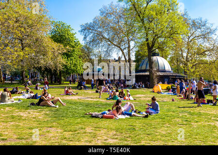 21st April 2019 - People sitting on the grass in the sun outside the Pavilion Cafe during Bank Holiday heatwave in Victoria Park, London, UK Stock Photo