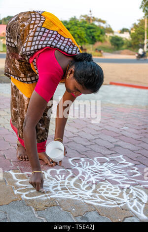 Vertical close up of a lady drawing rangoli patterns on her front doorstep, India. Stock Photo