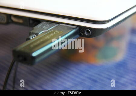 black flash drive with usb line in in white labtop slot.black flash drive in slot is tranfer information to labtop Stock Photo