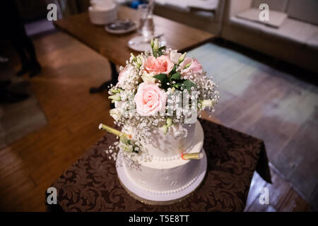 Wedding cake decorated with flowers on the table in a restaurant Stock Photo