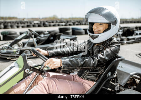 Young woman in protective helmet driving on the go-kart at the track outdoors Stock Photo