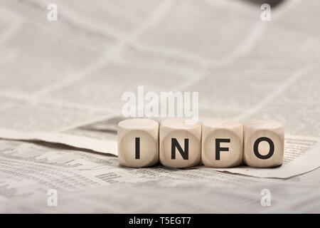 information concept - wooden cubes on newspaper forming word INFO Stock Photo